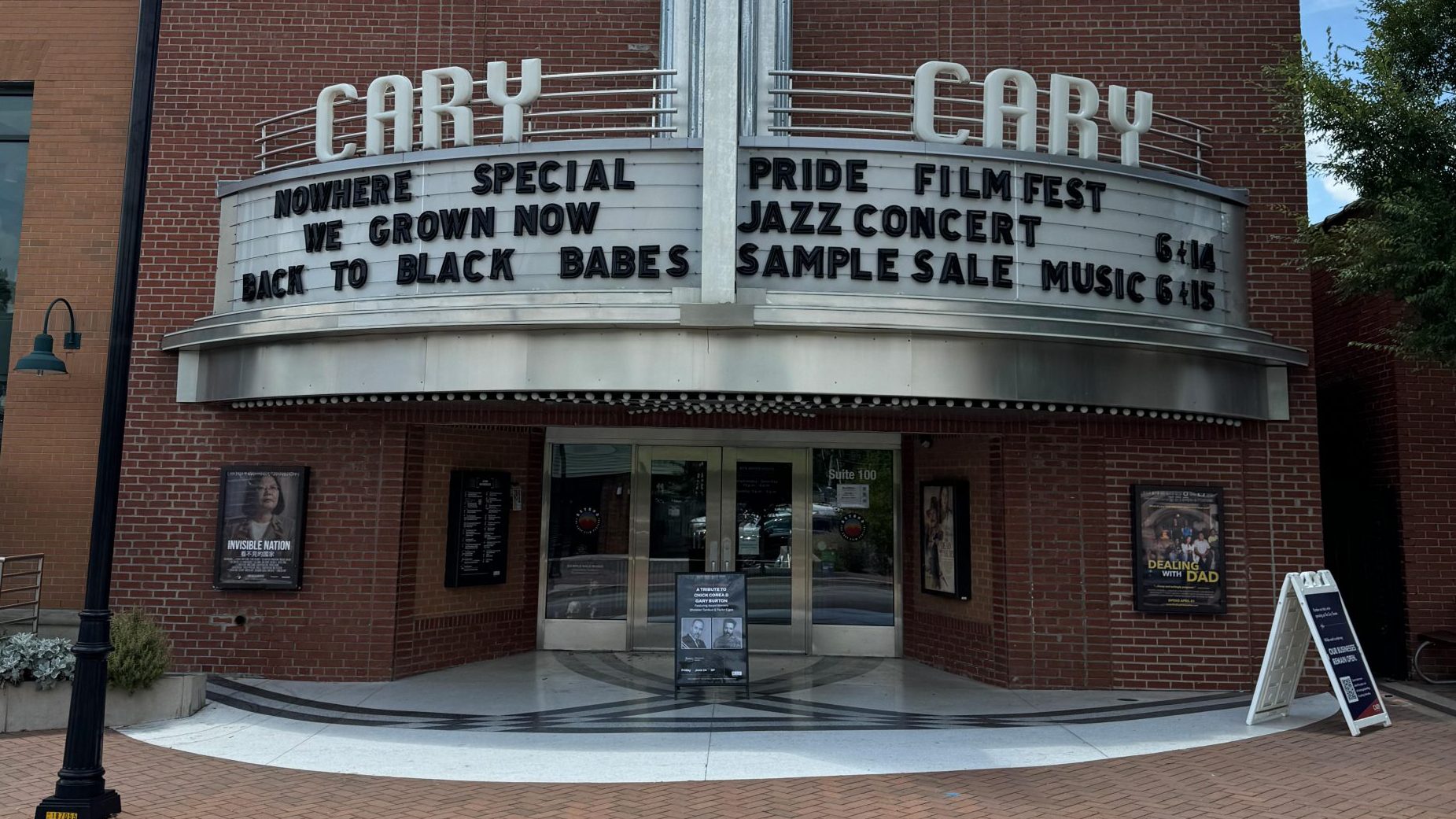 An art deco cinema facade with a vertical sign reading "CARY" and a marquee showcasing events like "Nowhere Special," "We Grown Now," "Back to Black Babes," the "Pride Film Fest," and an exciting AMAx Raleigh '24. Don't miss the Jazz Concert and Sample Sale Music on 6-15!