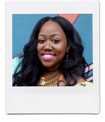 A woman with long, wavy black hair smiles at the camera. She is wearing a vibrant necklace and pink lipstick. The background is a colorful mural with abstract shapes. The photo has a white polaroid frame.